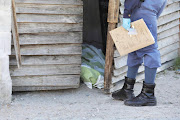 A police officer stands at the door where 25-year-old Sandile Sajini was killed, allegedly by police, during violent looting on Wednesday.