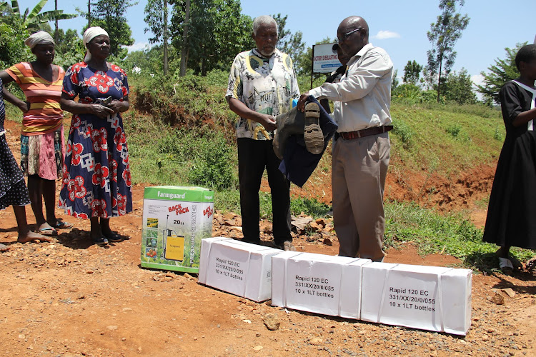 Farmer John Mose receives pesticide and personal protective equipment from Homa Bay director of agriculture Charles Nyayiera in Kobala, Rachuonyo South, on April 6, 2022
