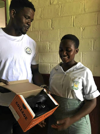 AmaZulu keeper Siyabonga Mbatha hands school shoes to a school girl.