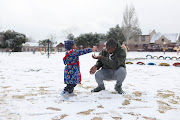 Edward Modiba plays with his son Motheo Modiba in the snow,  10 July 2023, at Jackson Dam in Alberton, South of Johannesburg.   