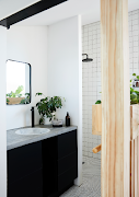 A half-height section of wooden panelling, topped with built-in planters and including a long towel rail on the bathroom side, separates the Hitchcocks’ bedroom from the shower, basin and vanity sections of the main bathroom. There’s plenty of under-counter storage in the custom vanity unit, which also includes a basin by WOMAG (womag.co.za) and tapware by Gio Plumbing (gioplumbing.com), who also made the shower rose. 