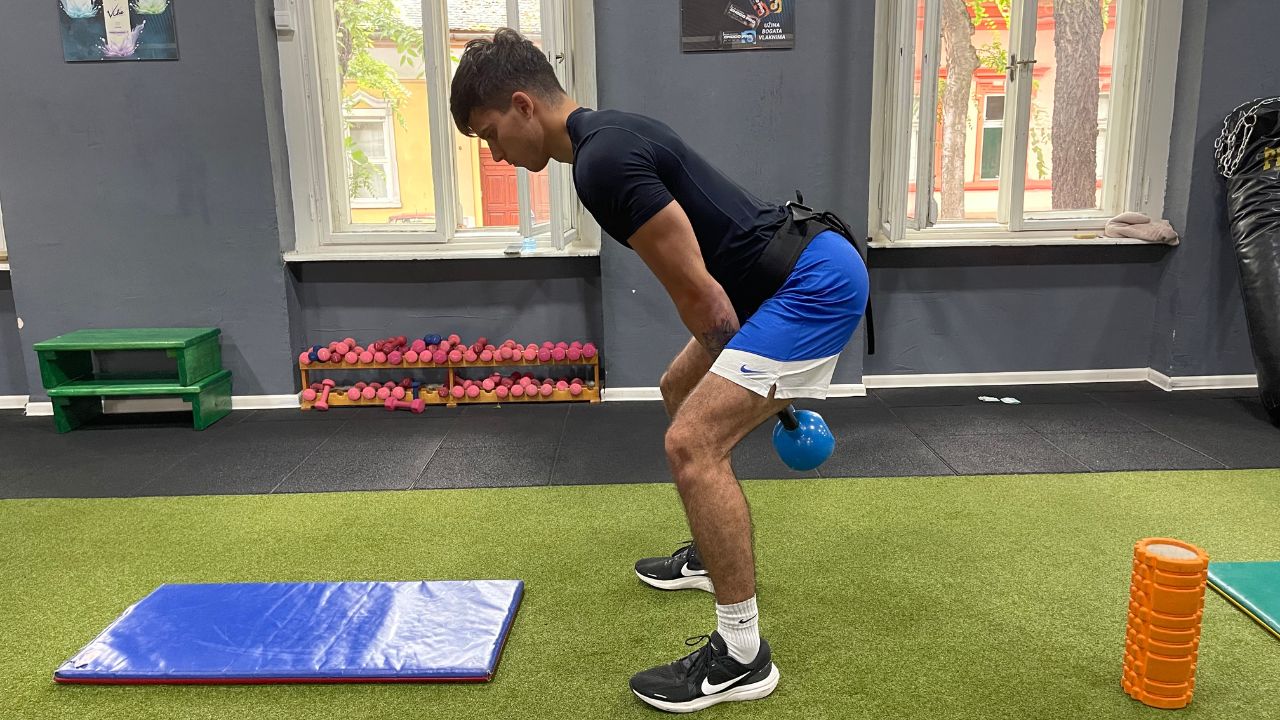 Vanja performs kettlebell swings for the lower back in the commercial gym setup.