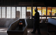 Johannes Mandlathi, a carpenter at Malusi Coffin Manufacturers in Emdeni, Soweto primes a coffin before hand-painting it. The manufacturers say demand for coffins and caskets has gone up due to the number of Covid-19 related deaths.