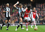 Bukayo Saka of Arsenal is challenged by Matt Ritchie of Newcastle United in their Premier League match at Emirates Stadium in London on November 27 2021.