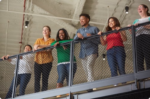 Un grupo de 6 empleados de Google de diferentes orígenes, mirando hacia el balcón de una oficina.