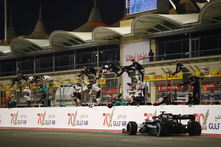 Lewis Hamilton of Great Britain driving the (44) Mercedes AMG Petronas F1 Team Mercedes W11 crosses the finish line to win as Mercedes team members celebrate on the pitwall during the F1 Grand Prix of Bahrain at Bahrain International Circuit on November 29, 2020 in Bahrain, Bahrain.