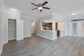 Open concept living and kitchen areas with wood plank flooring, a ceiling fan, light gray walls, and white trim and doors