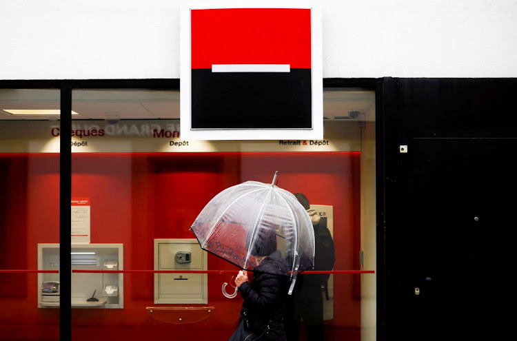 A person holds an umbrella as the logo of French Bank Societe Generale is seen outside a bank building in Saint-Sebastien-sur-Loire near Nantes, France on May 4 2021. Picture: REUTERS/Stephane Mahe