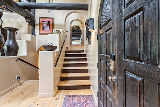 Interior staircase with dark wooden door in this luxury house for sale in Santa Fe ($1,950,000)