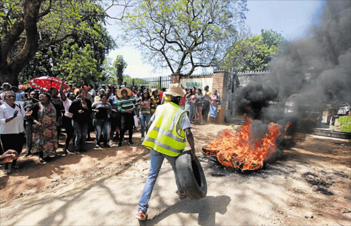 BAYING FOR BLOOD: Chaos ensued at the Qumbu Magistrate’s Court yesterday as hundreds of people protested, burning tyres at the main gate and stoning cars Picture: LULAMILE FENI