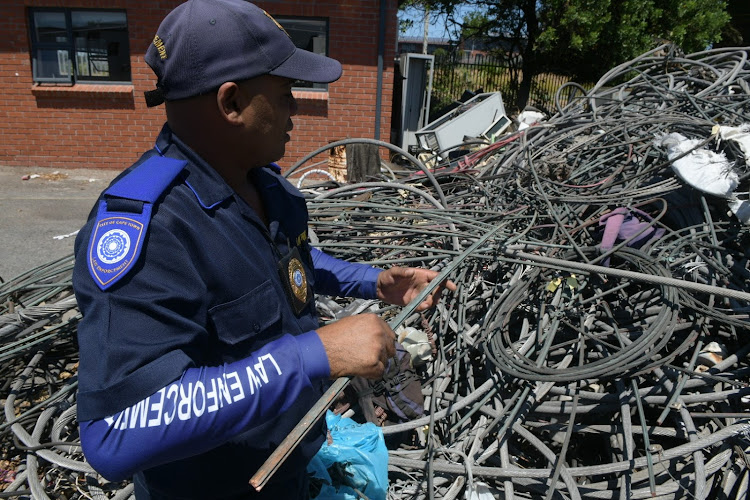 A member of Cape Town's rail enforcement unit with some of the 2,225m of stolen cable recovered in its first year.