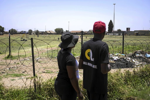 The father and mother of two different underage girls look across an empty playground in Tsakane, Ekurhuleni. Their children are among a group of girls who spend time smoking nyaope in the neighbourhood. They are accused of prostitution as well. / Greg Roxburgh