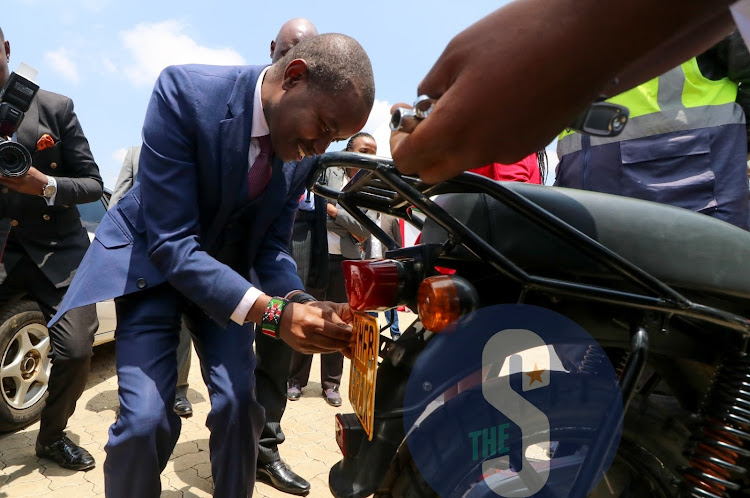 CS ICT Joe Mucheru fix the new number plate to a motorbike.