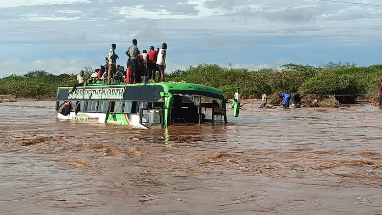 Passengers on top of the Wajir bound bus that was marooned by flood waters at Arer area near Tula along the Garissa-Nairobi road.