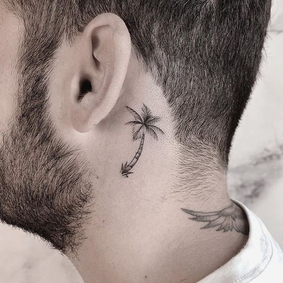 Guy rocks palm tree tattoo beside his earlobe 