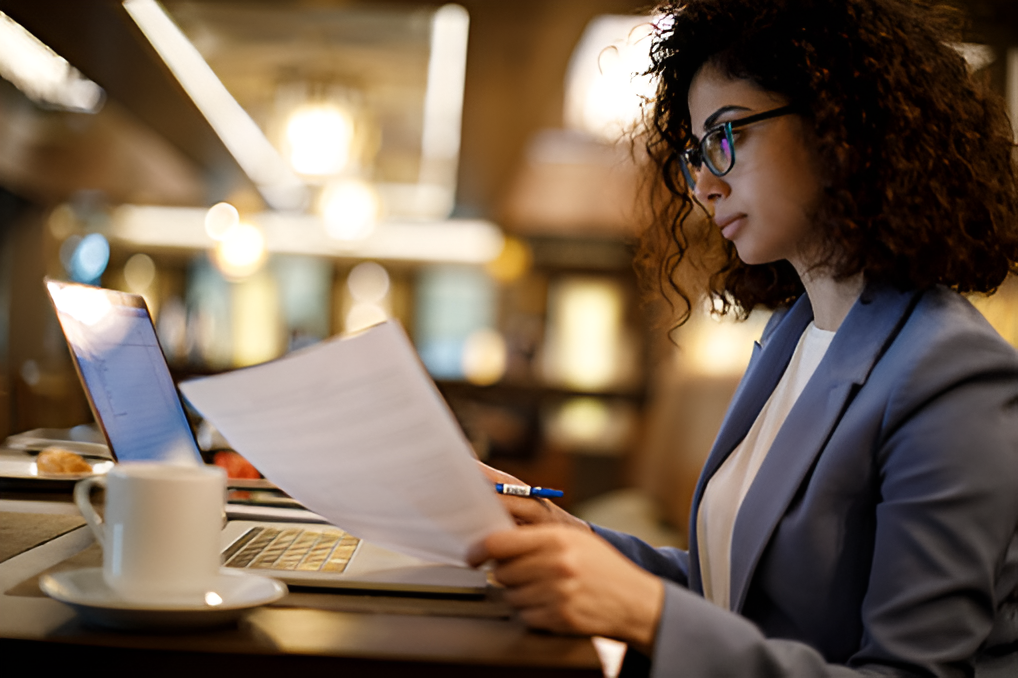 Woman looking at papers in front of computer