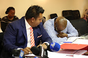 Sibusiso Chonco  bows his head, he is  accused of wrongfully appointing the principal contractor on the Nkandla upgrade projects . The disciplinary was adjourned due to his ill health. He is flanked by his attorney Adrian Moodely as  the National Department of Public Works Advocate Clement Kulati  tries to pursuade  Chairperson Thulani Khuzwayo that  he is well enough for the  disciplinary to continue