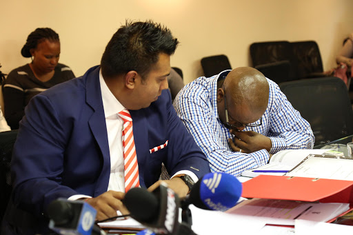 Sibusiso Chonco bows his head, he is accused of wrongfully appointing the principal contractor on the Nkandla upgrade projects . The disciplinary was adjourned due to his ill health. He is flanked by his attorney Adrian Moodely as the National Department of Public Works Advocate Clement Kulati tries to pursuade Chairperson Thulani Khuzwayo that he is well enough for the disciplinary to continue