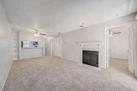 Spacious apartment living room with a fireplace, built-in shelves, and an open doorway to the kitchen area.