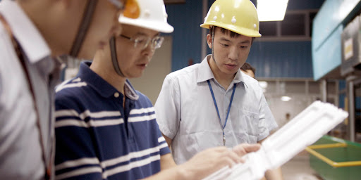 A group of three men looking at packaging material