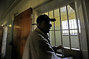 Ahmed Kathrada peers into a cell during a tour of Robben Island in 2015.