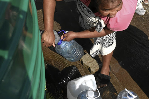 A woman fetches water from a jojo tank outside Mofumahadi Manapo Mopeli Hospital in Phuthaditjhabal. The hospital is also hit by water shortages.