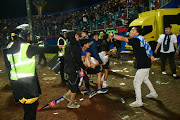 Supporters evacuate a man due to tear gas fired by police during the riot after the football match between Arema vs Persebaya at Kanjuruhan Stadium, Malang, East Java province, Indonesia, October 2, 2022.
