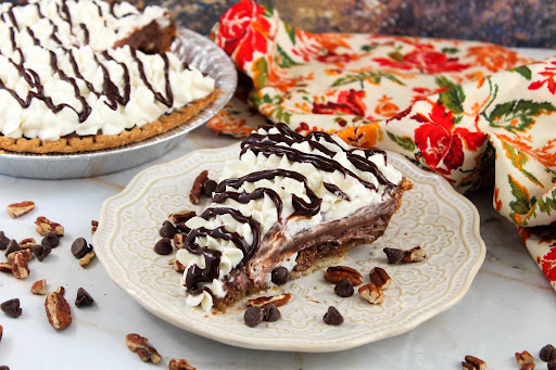 A slice of Chocolate Pecan Pie With Chocolate Pudding on a plate.