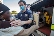 Paramedic Mathew Rosenberg prepares an injured resident for treatment outside the volunteer ambulance in Imizamo Yethu, Hout Bay.
