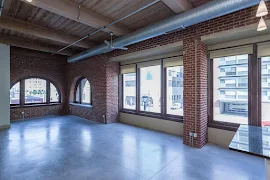 Living room with cement floors, exposed ductwork, floor-to-ceiling windows, arched windows, and brick walls