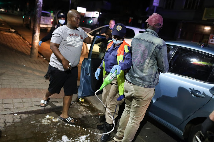 Law enforcement officials confiscate and pour alcohol onto a street in Johannesburg at the start of lockdown.
