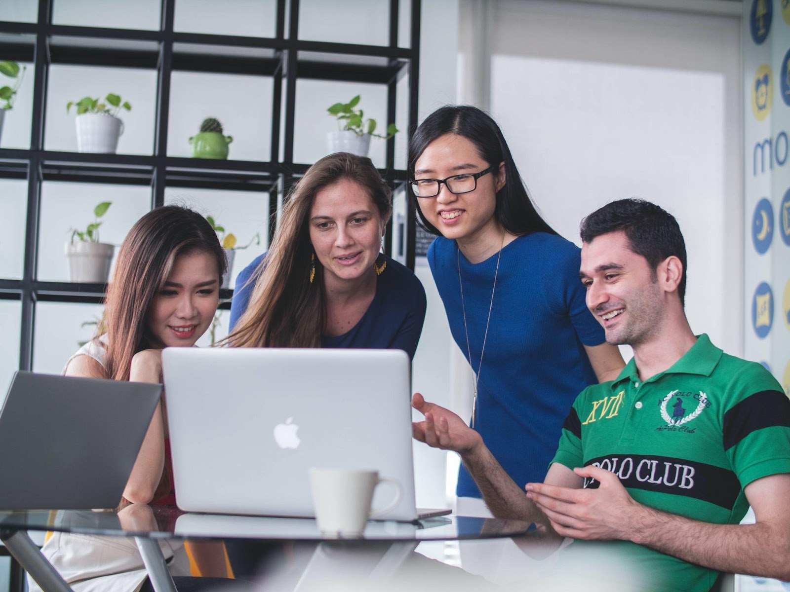 Group of four People Sitting at One Computer and Smiling 