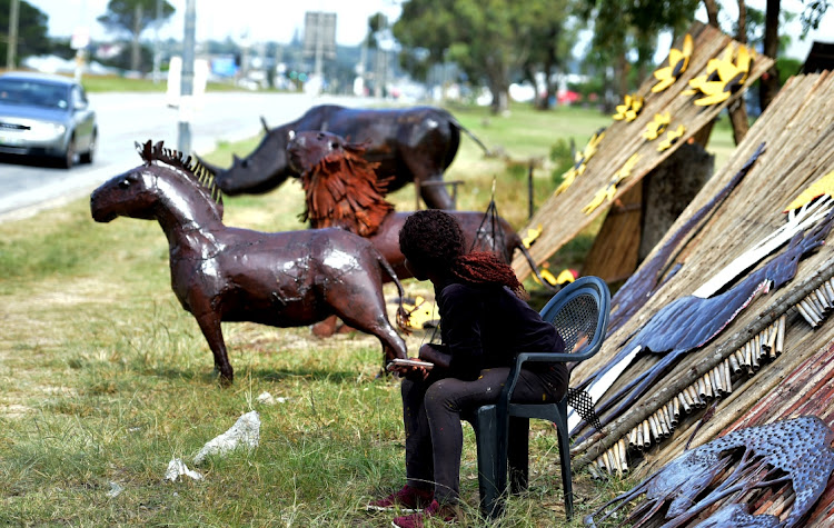 HOPE TAKES ROOT: Shuvai Ndava, 21, with the sunflowers she and her husband make from recycled tin displayed on the verge of the William Moffett Expressway