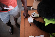 A ZEC election officer marks a voter's finger during the Zimbabwean harmonised elections at Emakhandeni Secondary School in Bulawayo, Zimbabwe.