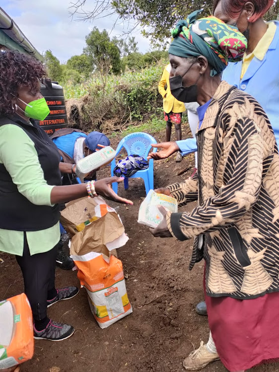Wanjiku Gachungi, a California-based preacher, hands over food donation to a widow in Kiambogo village in Laikipia County