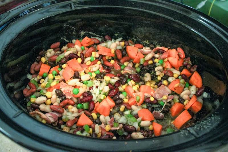 Bacon, Onion, Peppers, Carrot, Celery, Garlic, Green Beans, Peas, And Beans In A Slow Cooker.