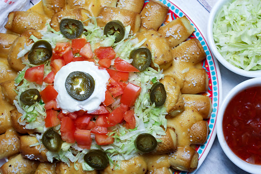 Pretzel nachos with beer cheese sauce and toppings.