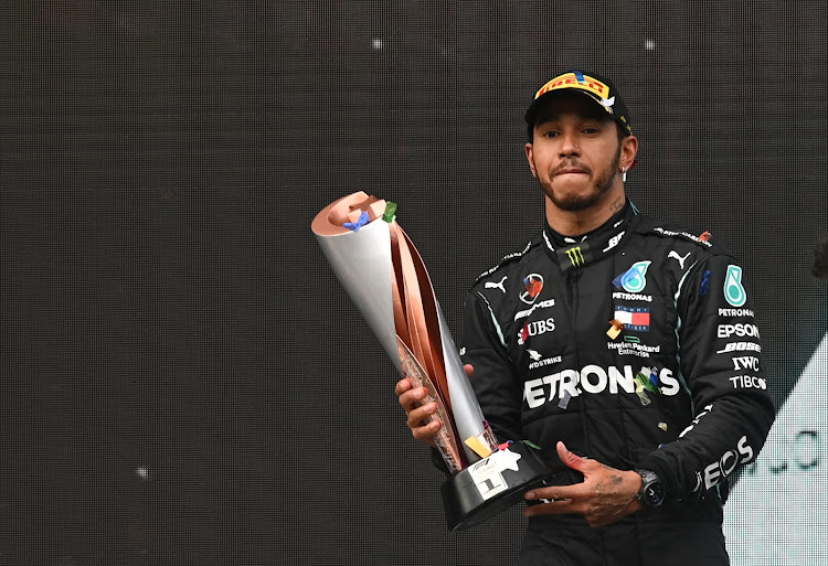 Mercedes' Lewis Hamilton celebrates on the podium with a trophy after winning the race and the world championship
