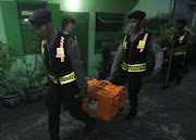 Police carry protective cases with evidence following the search of a house by the Densus 88 anti-terrorism unit in Ampel Kembang, Surabaya, East Java, Indonesia December 9, 2017.