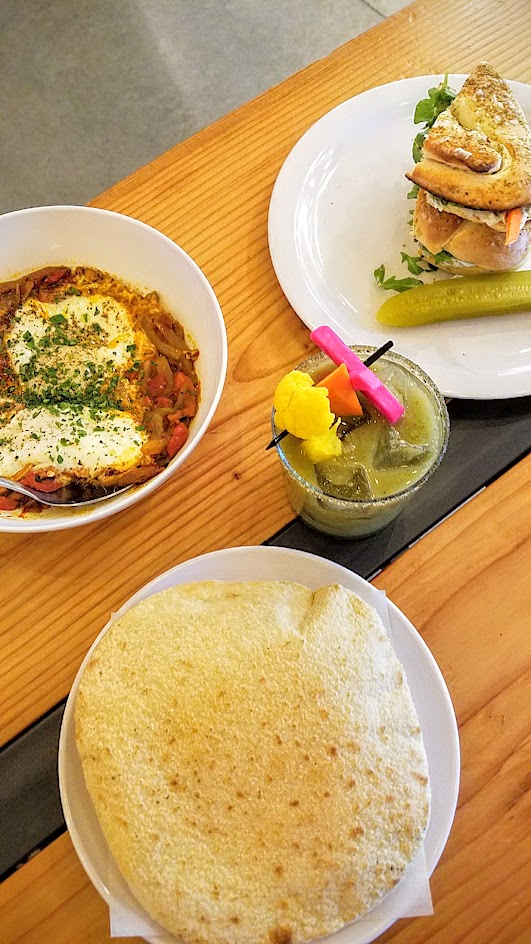 Shalom Y'all options for brunch at Pine Street Market of Shakshuka with tomatoes, peppers, baked eggs; a Jerusalem Bagel Sandwich with house-smoked mackerel, pickles, za’atar, and herbed labneh; and a Shalom Mary with vodka, tomatillo, cucumber, celery, s’hug, and za’atar salt
