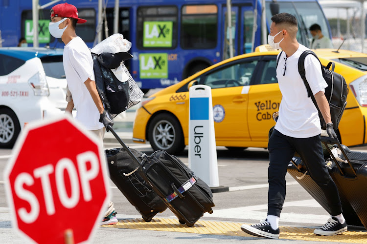 Travelers arriving at Los Angeles International Airport look for ground transportation during a statewide day of action to demand that both ride-hailing companies Uber and Lyft follow California law and grant drivers "basic employee rights'', in Los Angeles, California, U.S., August 20, 2020. REUTERS/Mike Blake