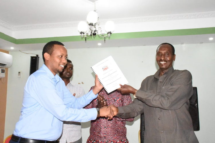 Wajir Health executive Abdihakim Noor and Governor Mohamed Abdi hold a performance contract document on Wednesday