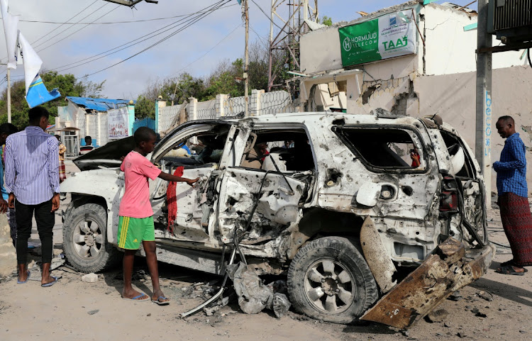 Civilians inspect the wreckage of a car destroyed at the scene of a militant attack at the Elite Hotel in Lido beach, Mogadishu, Somalia, on August 17 2020.