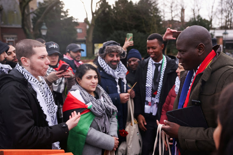 Minister of justice Ronald Lamola stands near pro-Palestinian protesters after addressing the media near the International Court of Justice on the day judges hear a request for emergency measures by SA to order Israel to stop its military actions in Gaza, in The Hague, Netherlands, on January 12 2024.