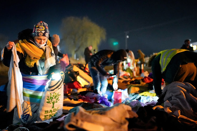 A woman searches through donated clothes for useful items after she and her children fled Ukraine for Poland. File photo.