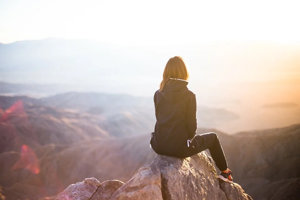 Woman sitting on a cliff thinking about how to travel peacefully in a pandemic 