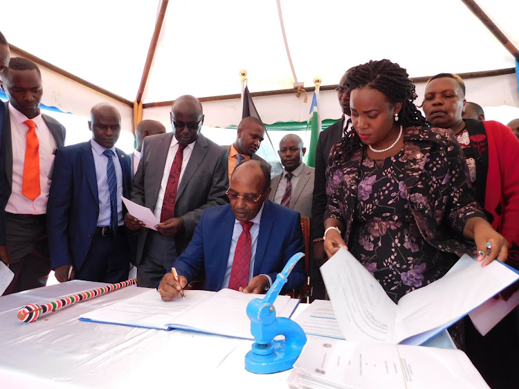 Rose Wamuiya (former trade executive) (R), Nyandarua County Secretary Hiram Kahiro, Simon Ng'ang'a (Former Water Tourism and Natural resources executive) and Lawrence Mukundi, Lands executive witness governor Francis Kimemia sign the Ol Kalou Municipal Charter on August 20, 2019.