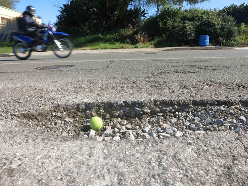 RIGHT WHEELS: An East London commuter has the right ride to avoid the the bang. The tennis ball gives an idea of the size of this pothole near Checkers on the Old Transkei Road and Cecil Lloyd intersection. Picture: MIKE LOEWE