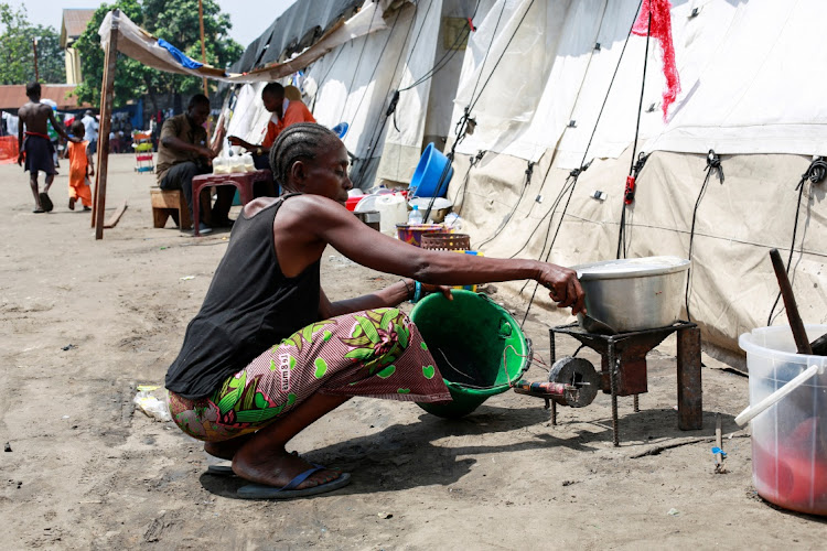 A woman cooks her food at Kingabwa emergency camp in Kinshasa, DRC, on January 30, 2024. REUTERS/JUSTIN MAKANGARA