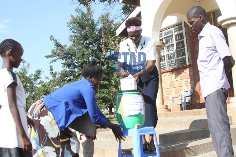 A woman washes her hands at the entrance of Power of Jesus Around the World church in Kisumu on March 15, 2020.